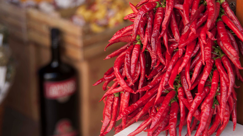 Calabrian chiles hanging in bunch with crates in the background