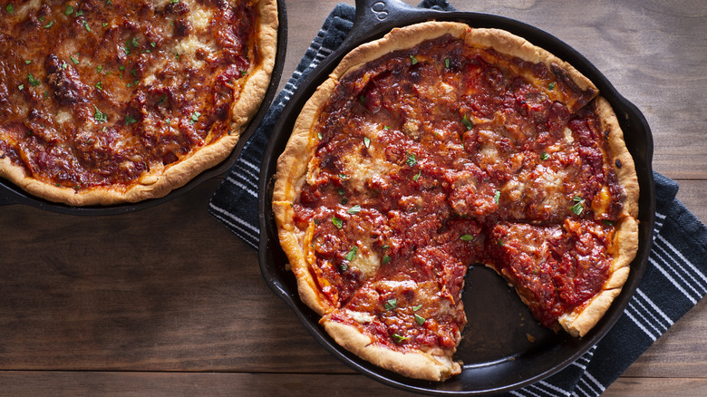 Deep dish pizza in cast iron pan on wood background