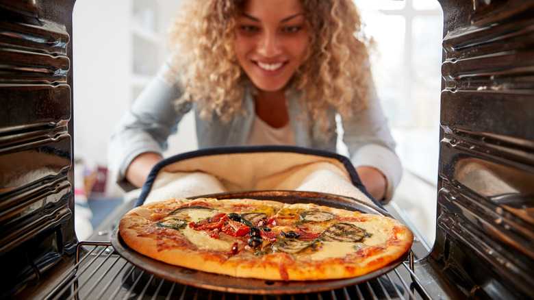 Woman reheating pizza in the oven