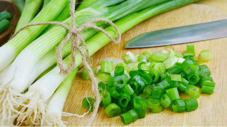 Chopped scallions on board with knife