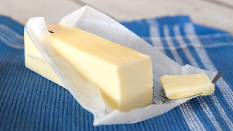 A stick of unwrapped butter on a blue and white towel