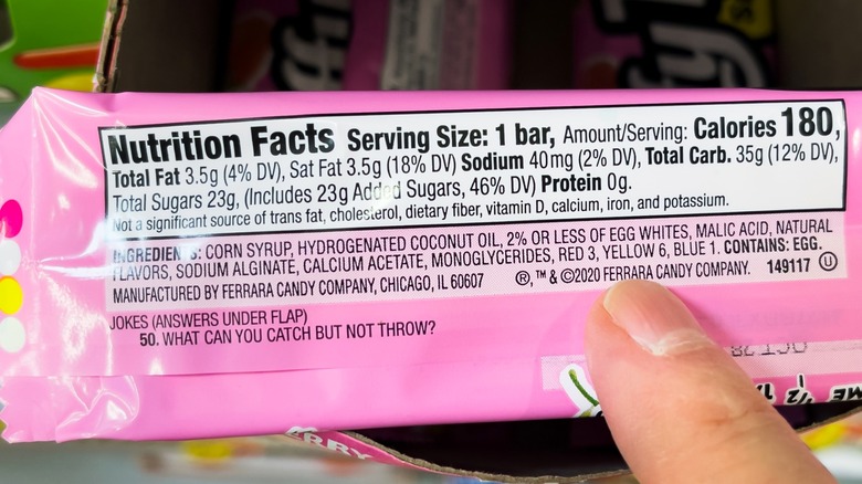 Person holding pink snack bar with nutrition facts listed