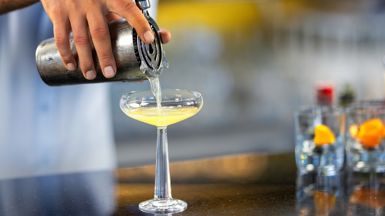 A chilled shaken cocktail being poured out into a glass