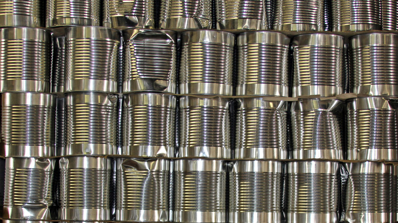 Stacks of unlabeled food cans, some with dents.