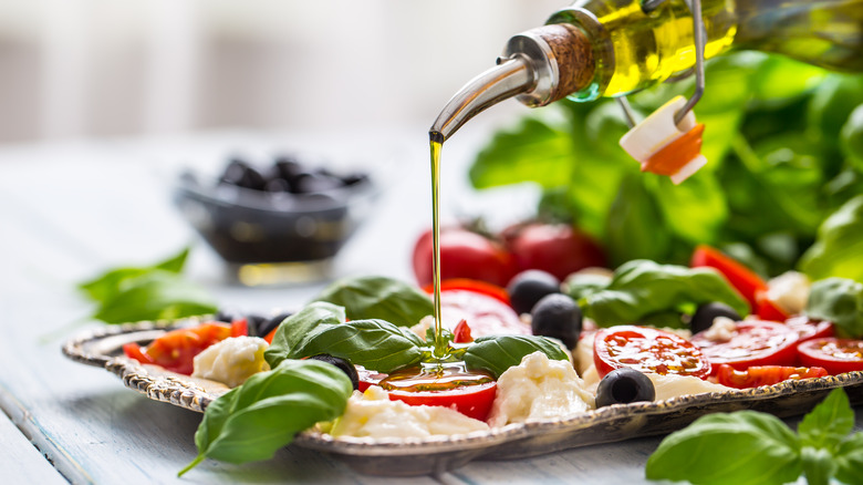 Pouring olive oil on a caprese salad