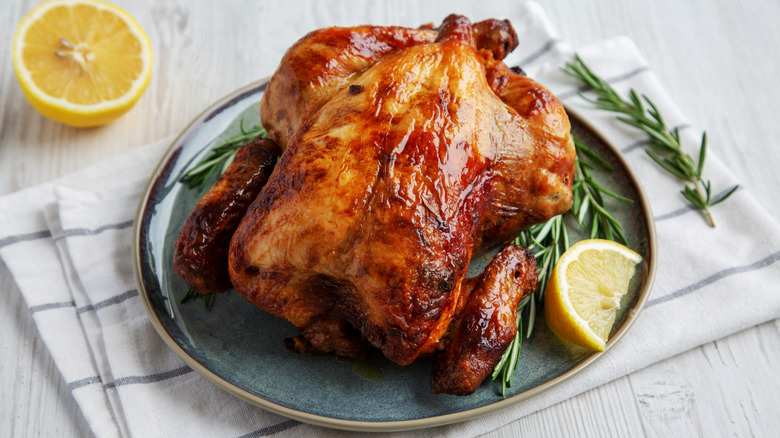 Roast chicken on plate with lemon and rosemary