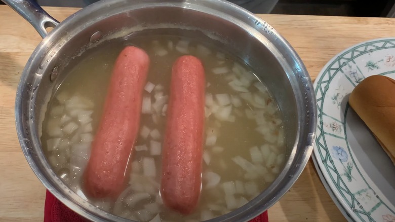 Hot dogs boiled in broth with onions