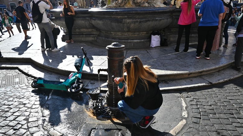 Woman filling a water bottle from a nasone