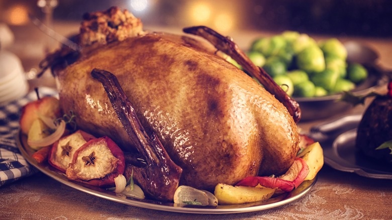 Roasted goose on tray with side dishes nearby