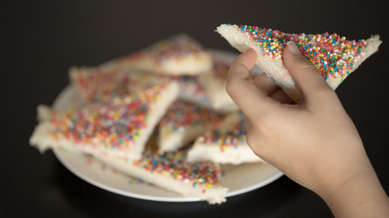 Hand holding triangular slice of fairy bread