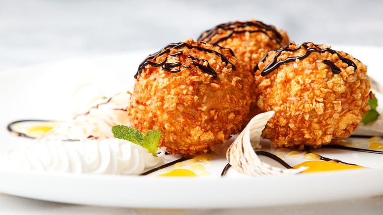 three fried ice cream balls covered in chocolate syrup
