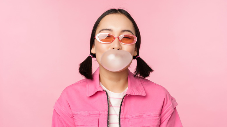 Woman with bubblegum bubble pink background.