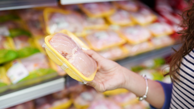 shopper looking at package of chicken at store