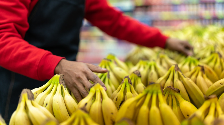 Store clerk stacks bananas in a supermarket