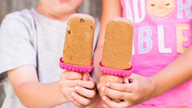 Two children holding homemade Pudding Pops on pink sticks