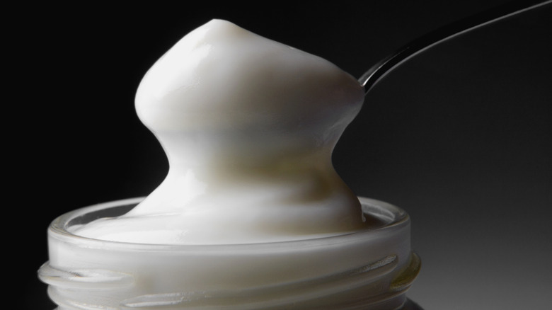 A spoonful of mayonnaise from a glass jar