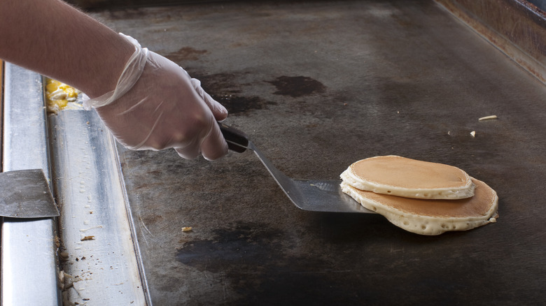 pancake about to be flipped on restaurant griddle