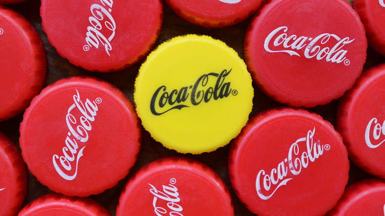 a yellow Coca-Cola bottle cap surrounded by red and white ones.