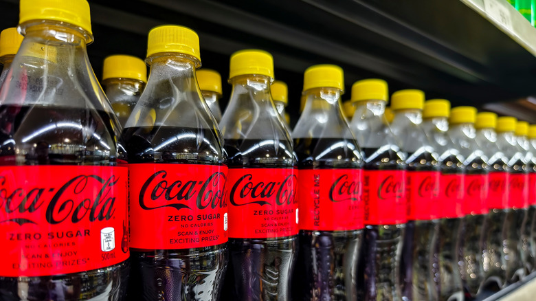 yellow capped Coca-Cola bottles on store shelf