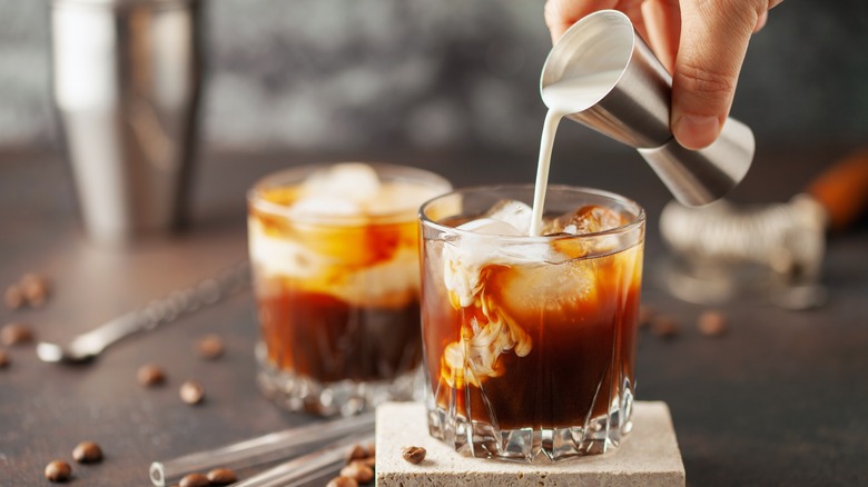 Glasses of white Russian cocktails beside coffee beans.