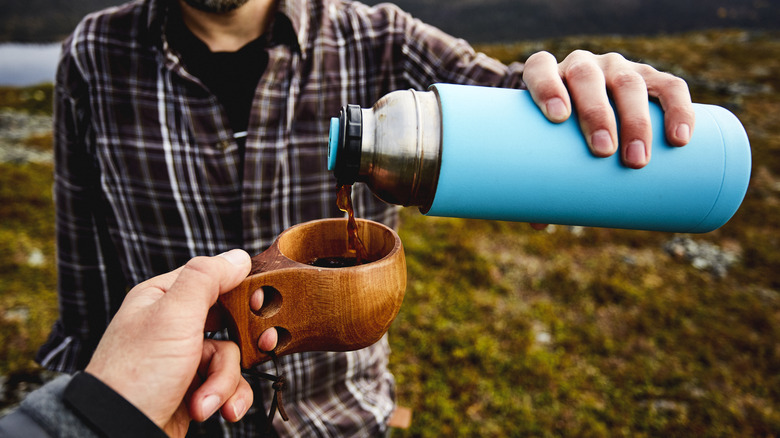 Person pouring coffee into a wood Finnish kuksa cup