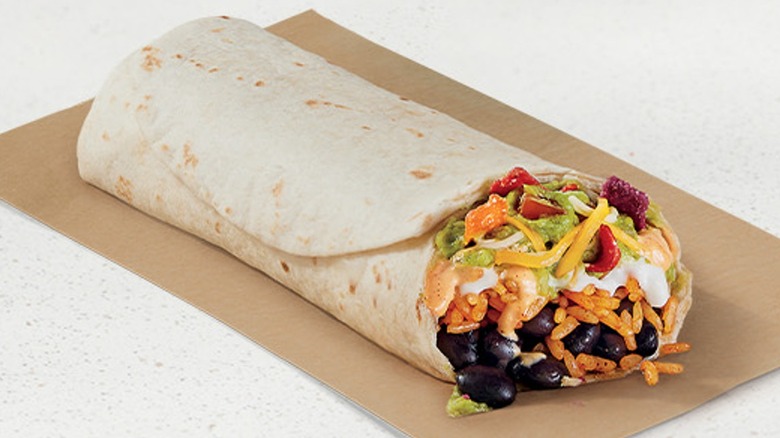 A Taco Bell Fiesta Veggie Burrito, open on one end, on a brown napikin