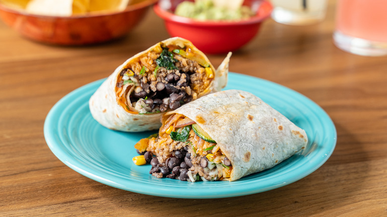 homemade veggie burrito with black beans and Mexican rice on a blue plate