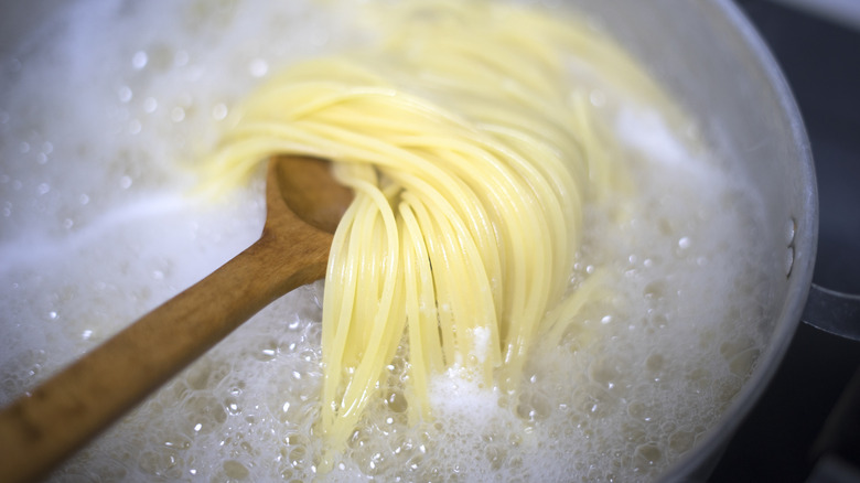 Wooden spoon in boiling pasta water