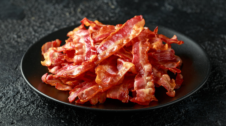 strips of crispy bacon stacked on a black plate