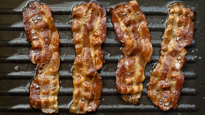 strips of bacon frying in a griddle pan