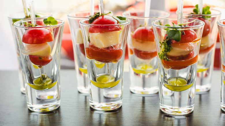 Shot glasses with cheese, tomato, herbs and olive oil
