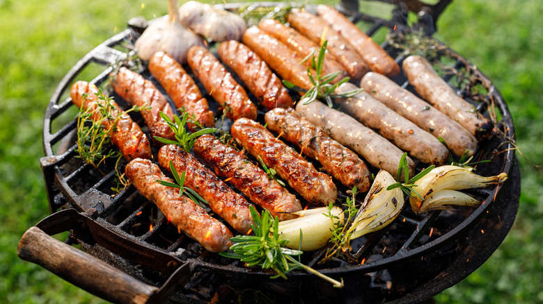 Bratwurst cooking on grill with vegetables
