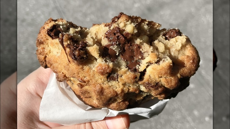 Thick chocolate chip cookie held with street in background