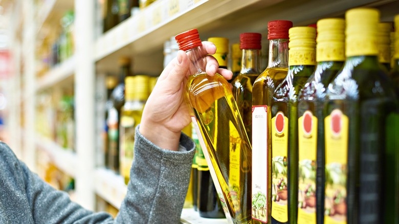selecting a bottle of olive oil from a shelf
