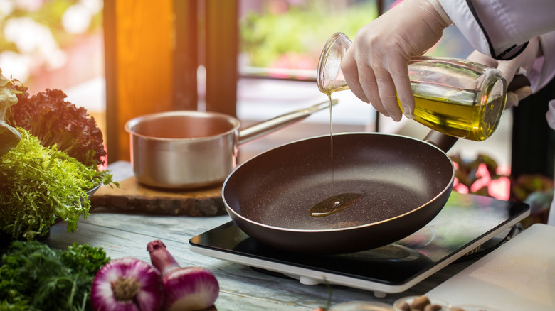 pouring olive oil into a saute pan