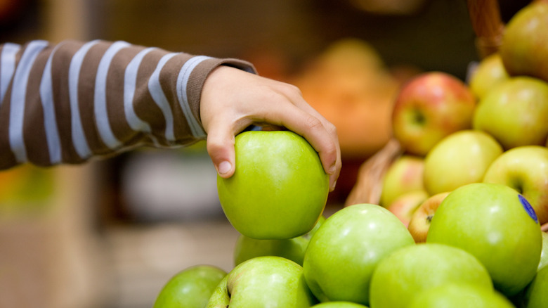 picking apple from grocery store shelf