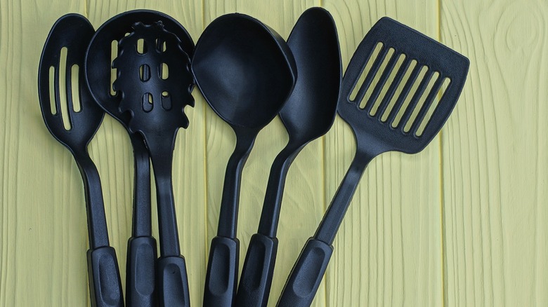 Black plastic kitchen utensils beige background