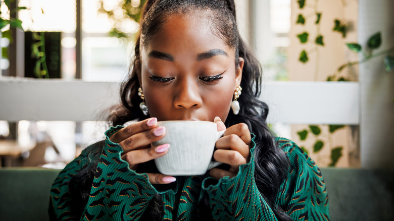 A young woman enjoys a mug of coffee