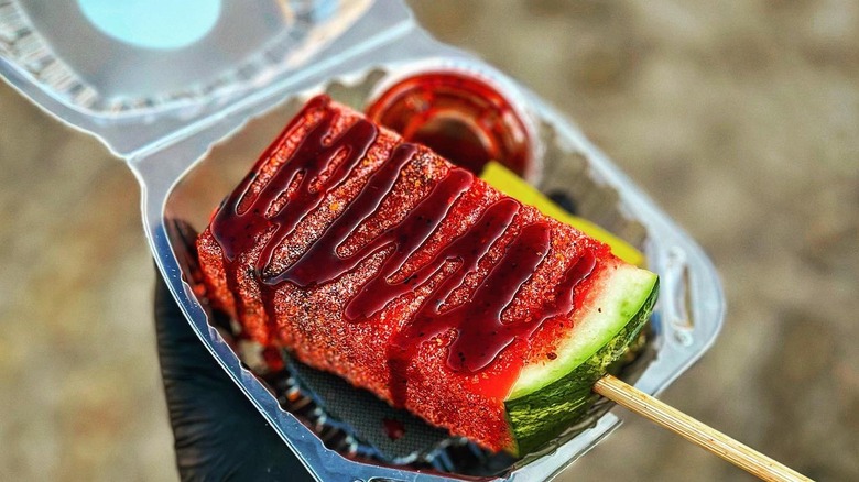 watermelon wedge on a stick wrapped in fruit leather and topped with chamoy and tajin