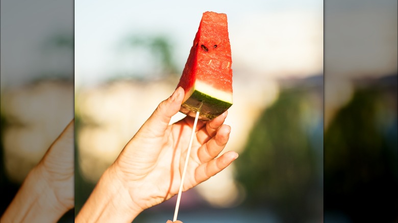 watermelon wedges on popsicle sticks against a blue background