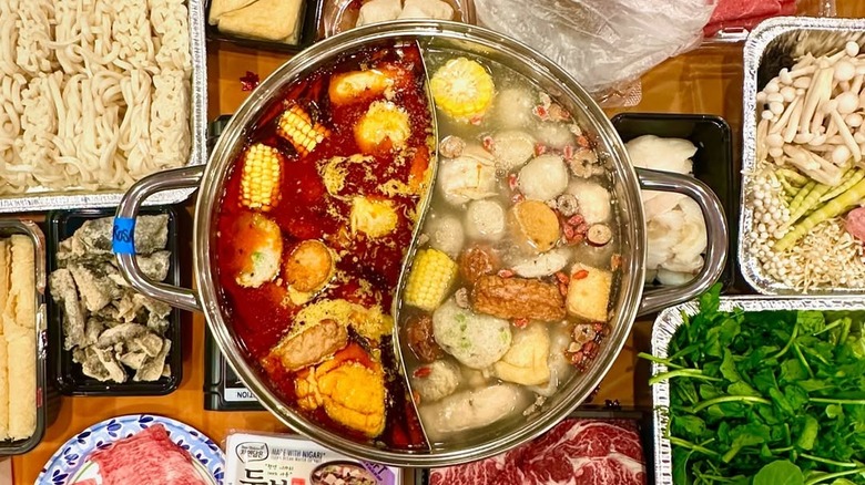 Overhead view of hotpot and other dishes at Maxi's Noodle, served on wood tabletop