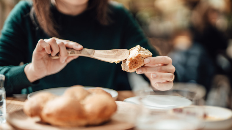 Woman applies butter to a piece of bread at a restaurant