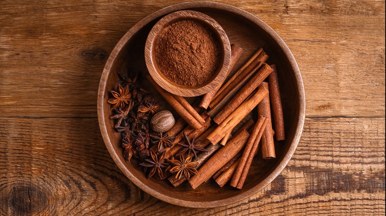 Nutmeg, cinnamon, star anise in wooden bowl