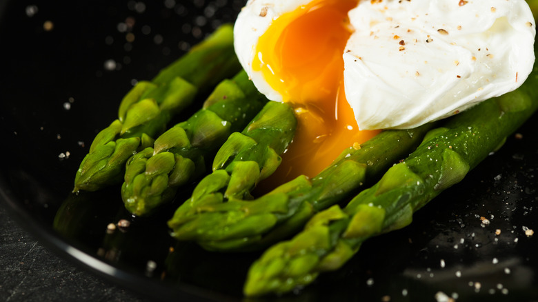 Poached egg with yolk running over blanched asparagus
