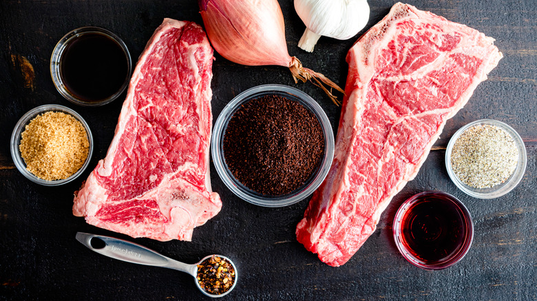 Raw steaks with ground coffee and dry rub ingredients