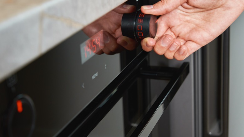 hand adjusting the temperature dial on an oven